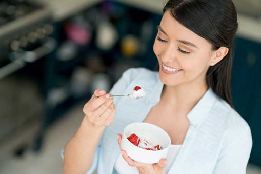 young, beautiful woman eating fruit pudding