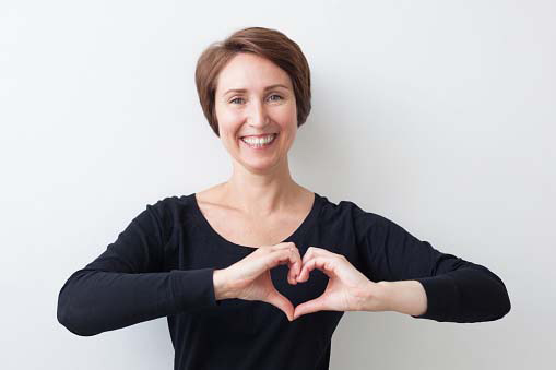 a happy woman feeling fit and making a heart with her hands