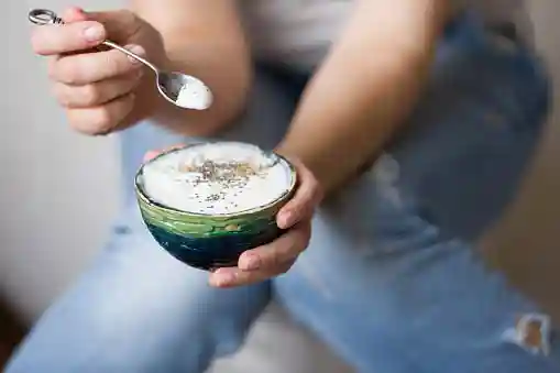 young woman holding a cup of yogurt promoting healthy eating