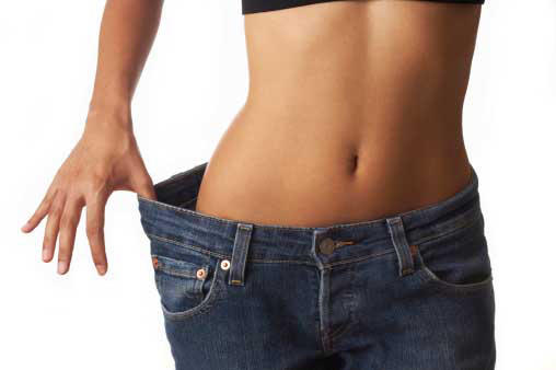  woman showing waist inch loss in jeans=